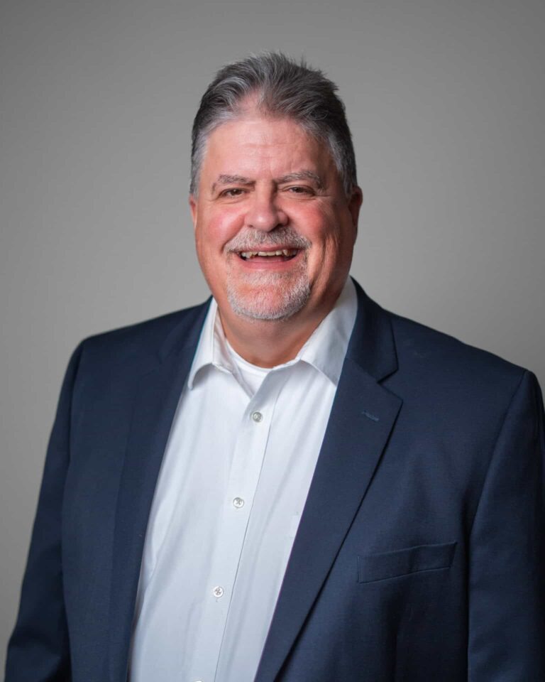 Smiling man in business attire from Asset Enterprises, embodying our mission to sustain your critical retail technology.
