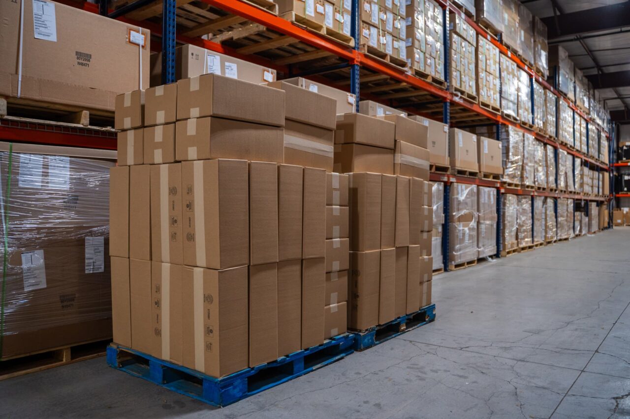 Warehouse with stacked cardboard boxes on pallets highlights why retailers are moving store builds off-site.
