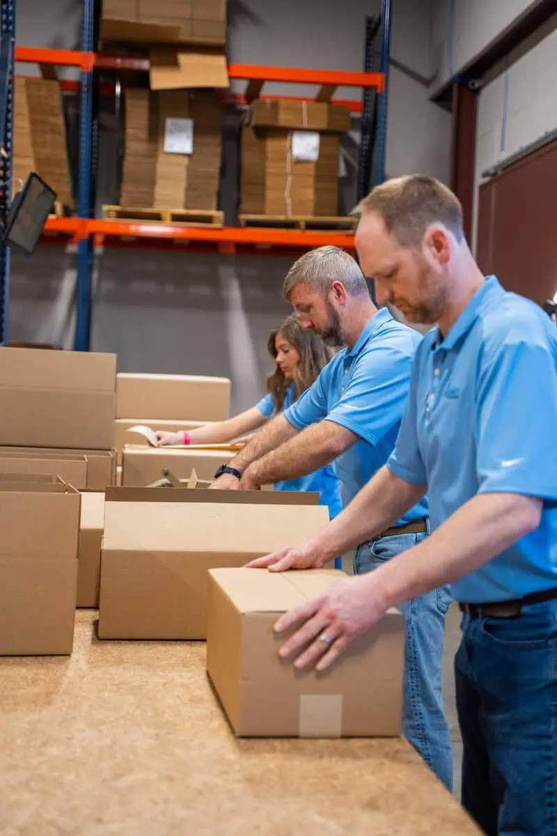 Team packing boxes, highlighting efficient product sourcing services for organizations needing a partner.