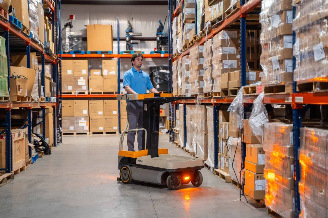 Warehouse employee utilizing automated equipment for asset disposition, managing boxes on shelves.