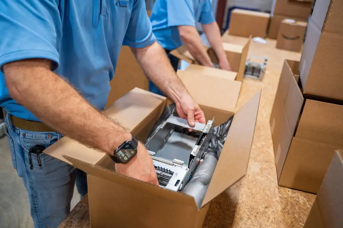 Technician packs refurbished technology equipment for repair test, ensuring cost savings and protection.