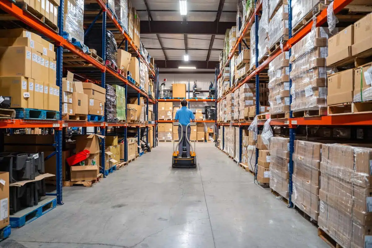 Warehouse worker on a lift among organized shelves, showcasing integration kitting and process design efficiency.