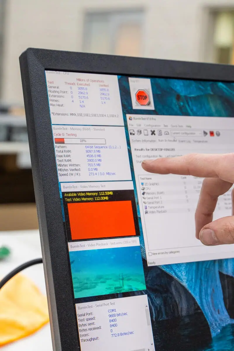 Monitor displaying system metrics for site maintenance with a technician's finger pointing at data.