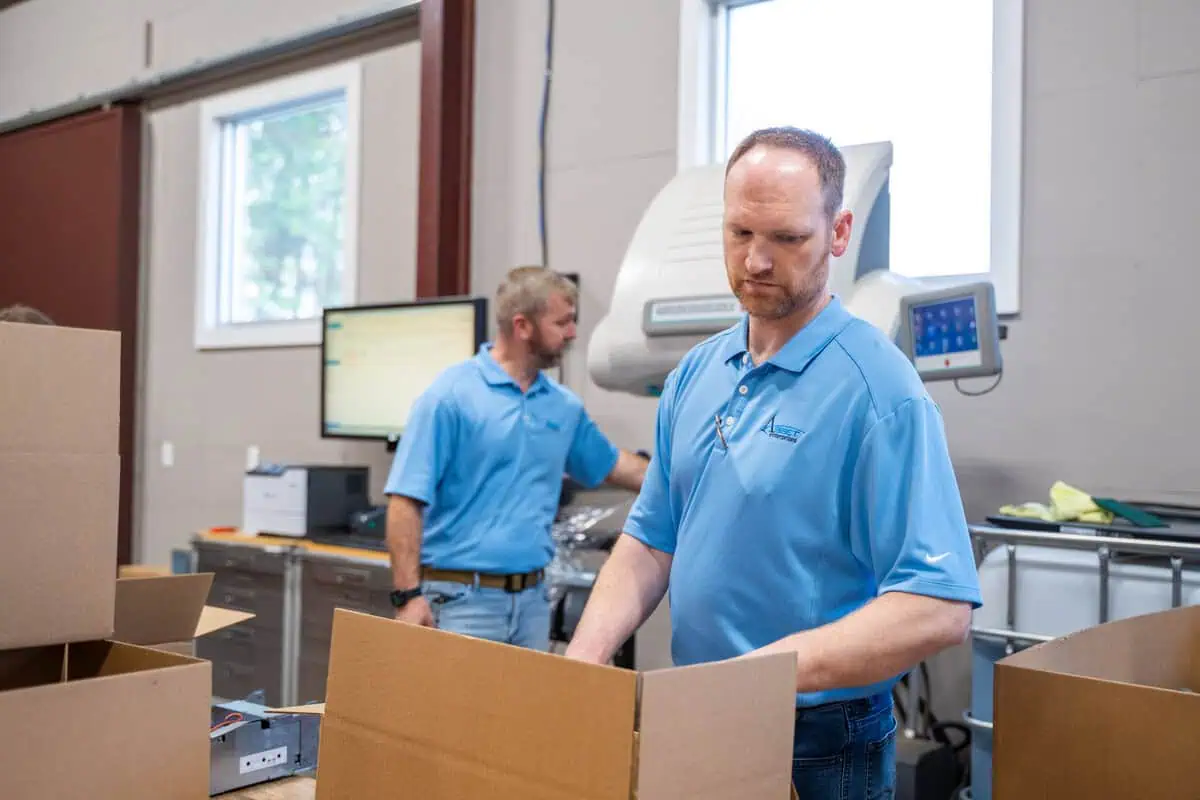 Employees in blue uniforms preparing equipment for secure destruction, ensuring assets leave your site safely.