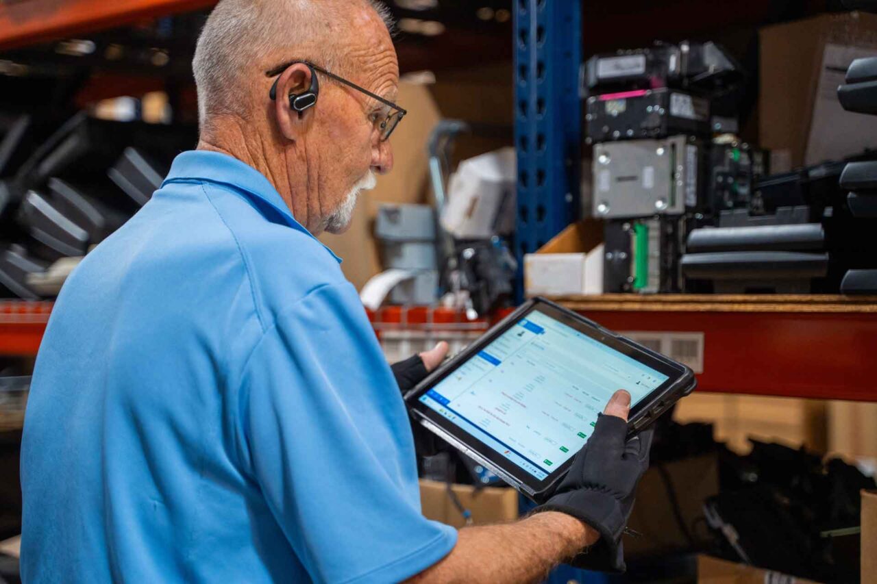 Technician using a tablet to manage hardware inventory, highlighting the right hardware choice in operations.
