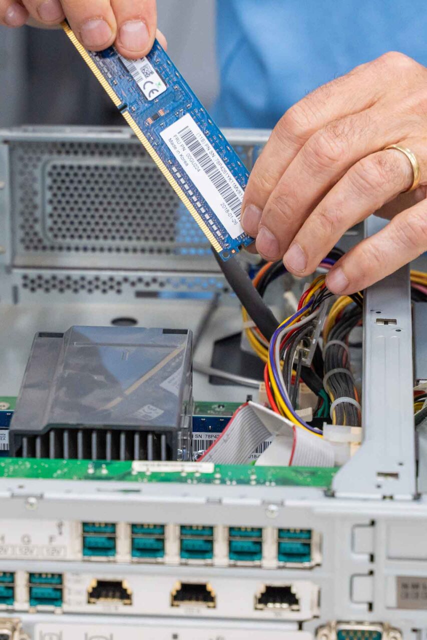 Inserting RAM into a computer, highlighting the importance of hardware choice to avoid friction downtime.