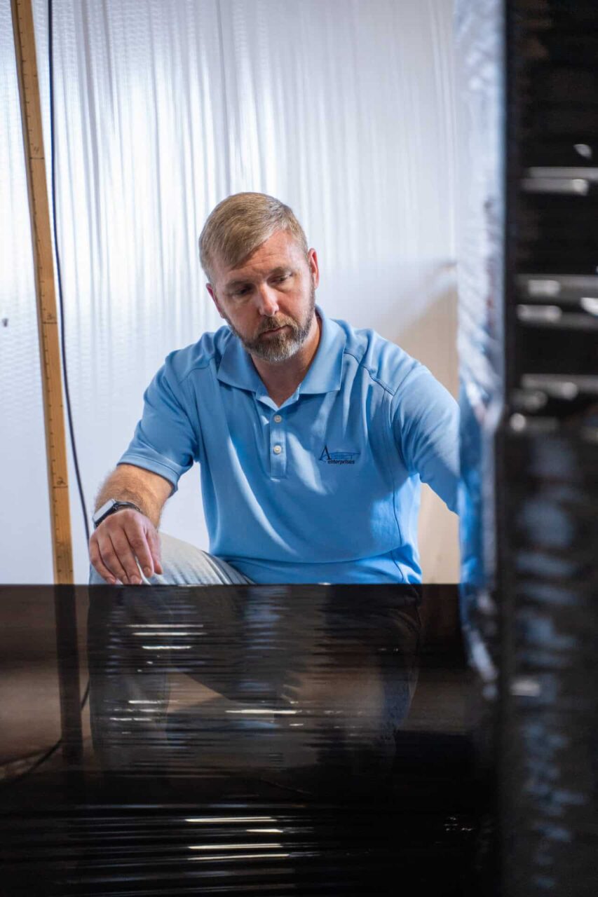 Man in blue shirt inspecting black hardware, exemplifying high-quality used hardware for maintenance operations.